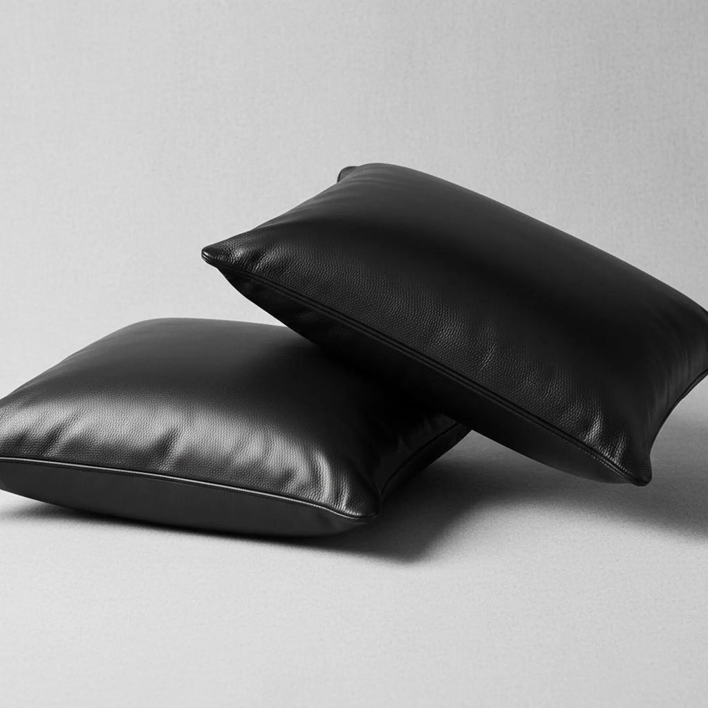 Two black leather pillows on a light gray background